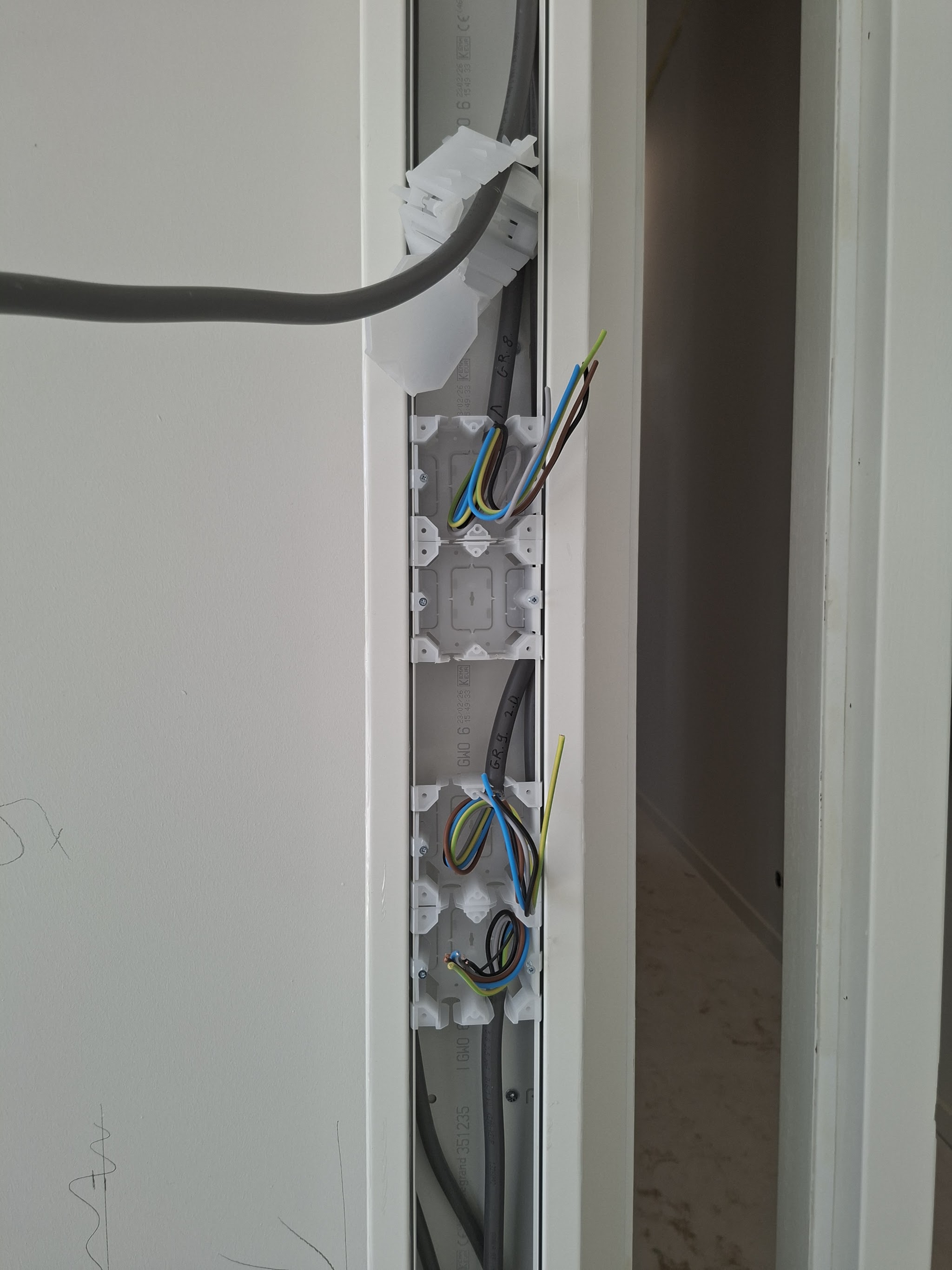 Inbouwdozen in een wandsleuf met per groep gelabelde kabels tijdens een verbouwing